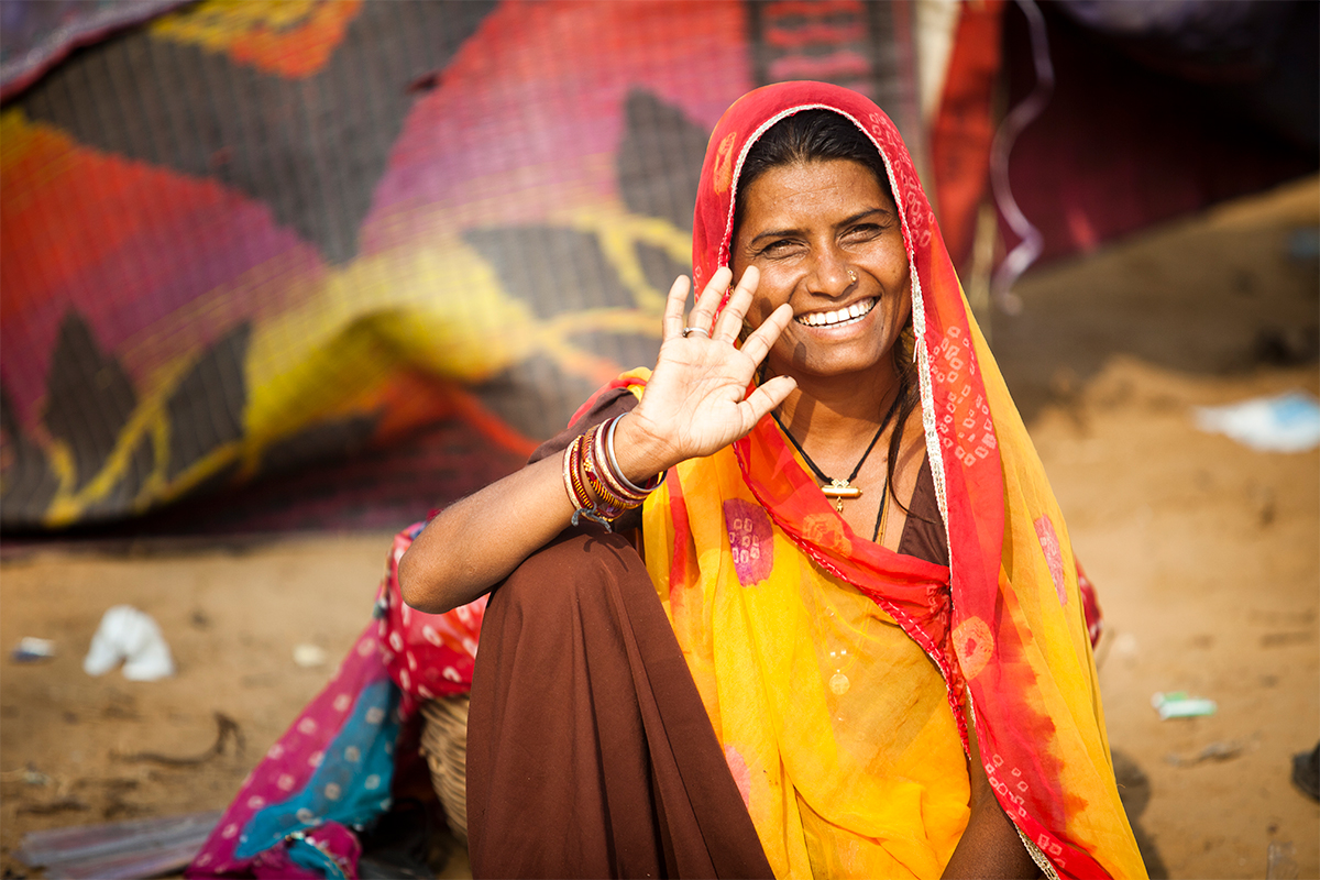 Smilende person i Delhi blant fargerike tekstiler i et marked